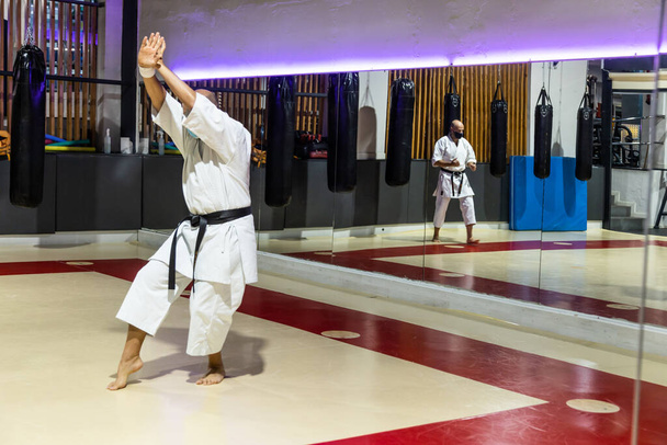 onherkenbaar jong volwassen man training karate in dojo met gezichtsmasker - Foto, afbeelding