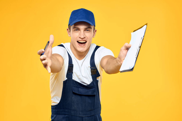 Homem em documentos uniformes de trabalho prestação de serviços serviço de entrega fundo amarelo - Foto, Imagem