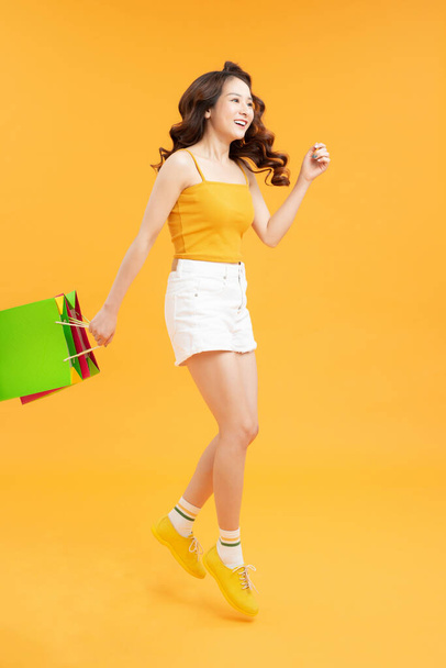 Big Sales. Girl Running With Shopping Bags Over yellow Background, - Φωτογραφία, εικόνα