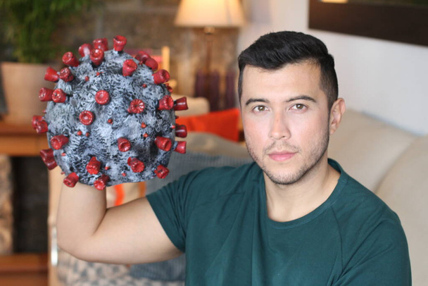 retrato de cerca del joven guapo sosteniendo el modelo de coronavirus en casa - Foto, Imagen