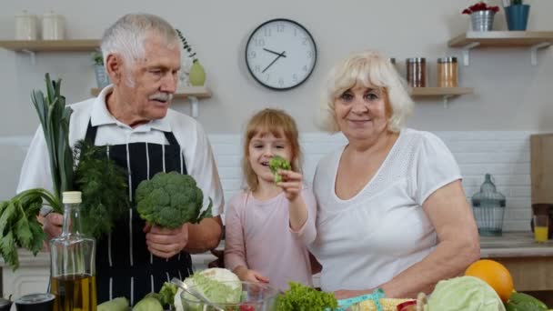 Chica con hombre maduro y mujer recomendando comer alimentos vegetales crudos. Alimentación saludable dieta - Imágenes, Vídeo