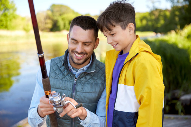 happy smiling father and son fishing on river - Photo, Image