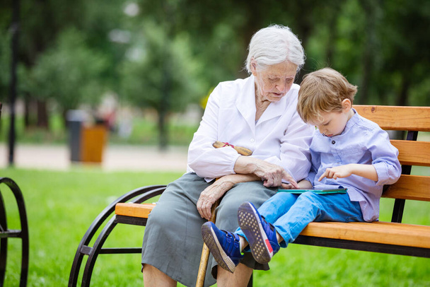 Mladý chlapec a jeho prababička pomocí tabletu v parku - Fotografie, Obrázek