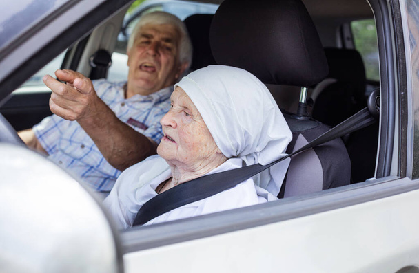 Senior woman taking driving lesson, male instructor pointing angrily at something - Foto, Imagem