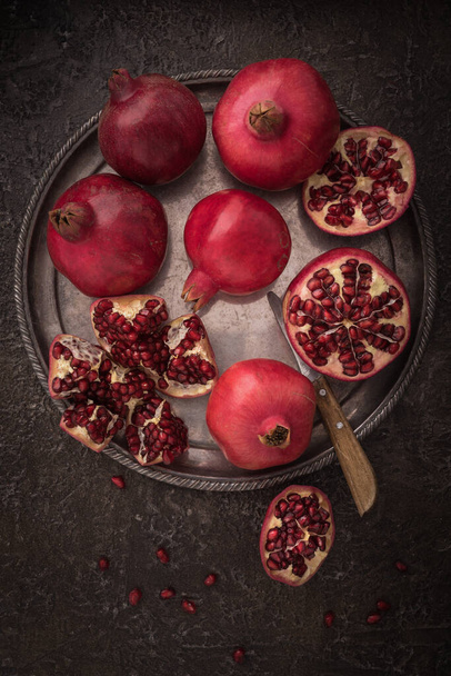 Fresh cuted pomegranates on the silver tray on dark rustic background flat lay. - Foto, Bild