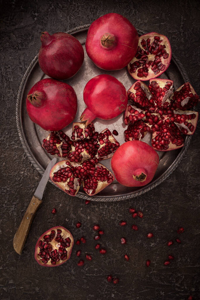 Fresh cuted pomegranates on the silver tray on dark rustic background flat lay. 2 - Фото, изображение
