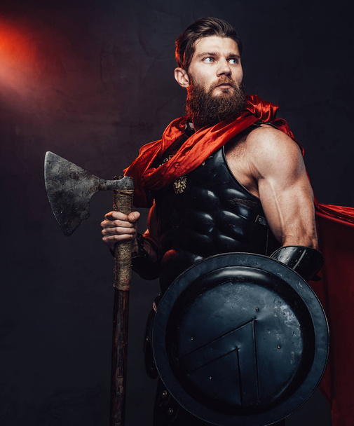 Romano guerrero blindado con capa y hacha en habitación oscura - Foto, Imagen