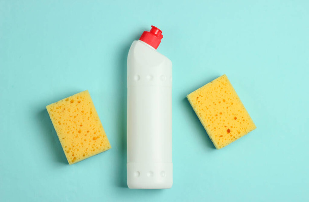 Cleaning concept. Detergent bottle, sponges on blue, pastel background. Top view - Photo, Image