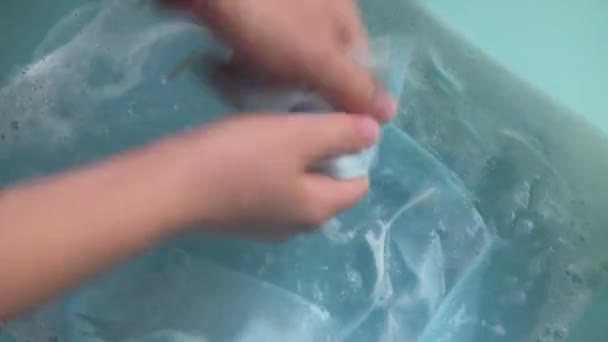 Großaufnahme einer weiblichen Hand, die eine medizinische Schutzmaske wäscht. Waschen von Einmalmasken zur Wiederverwendung aufgrund finanzieller Probleme während Covid-19. Coronavirus zerstört Wirtschaft und Gesundheit - Filmmaterial, Video