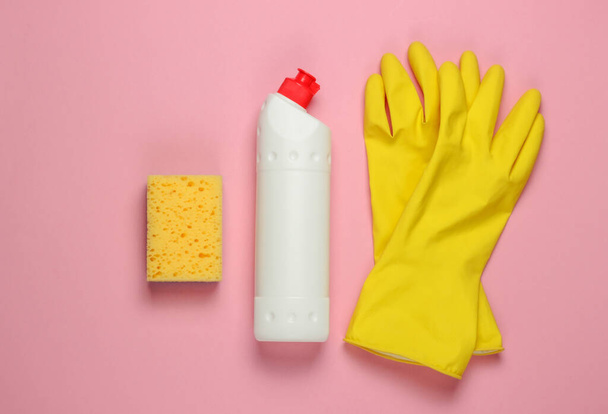 Pronto para a limpeza! Conceito de trabalho doméstico. Garrafa de detergente, esponja, luvas em fundo pastel rosa. Vista superior - Foto, Imagem
