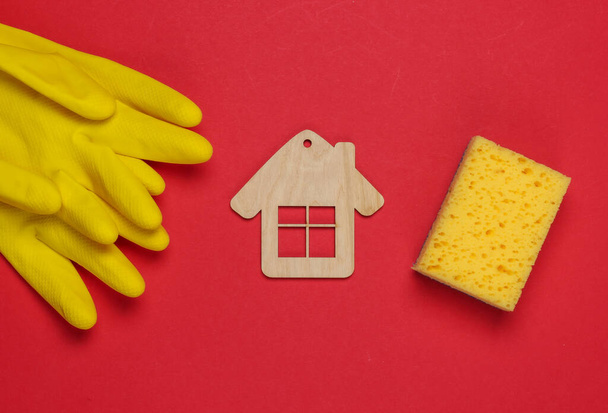 Housekeeping concept. Set of products for cleaning (gloves, sponge) and house figure on red background. Top view. - Photo, Image