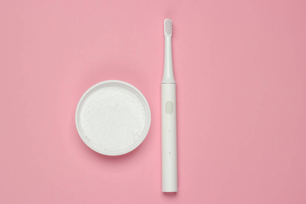 Modern electric toothbrush and tooth powder on a pink pastel background. Dental care concept. Top view. Minimalism - Photo, Image