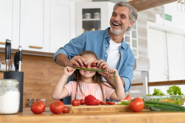 Cute little girl and her handsome dad are having fun while cooking in kitchen at home. - Valokuva, kuva