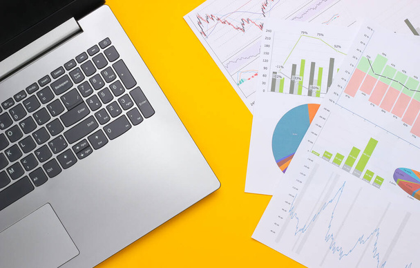 Laptop grafikonok és grafikonok sárga alapon. Üzleti terv, pénzügyi elemzés, statisztika. Felülnézet - Fotó, kép