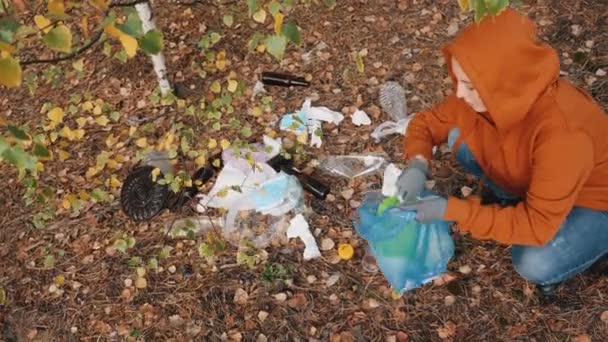 女性は森の中の袋にゴミを集める - 映像、動画
