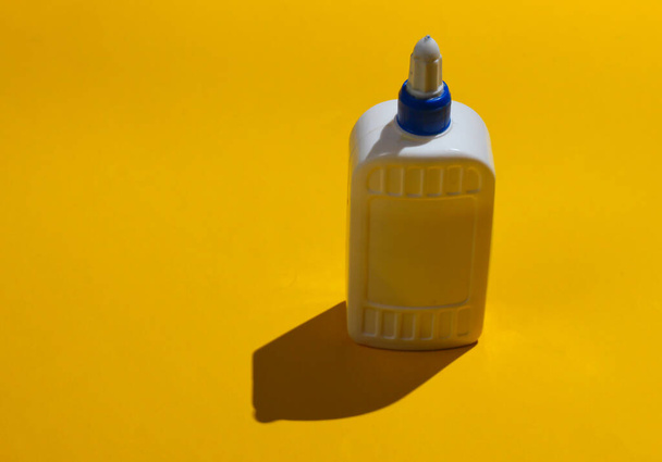 Egy üveg ragasztó sárga alapon. Stúdió lövés árnyékokkal - Fotó, kép