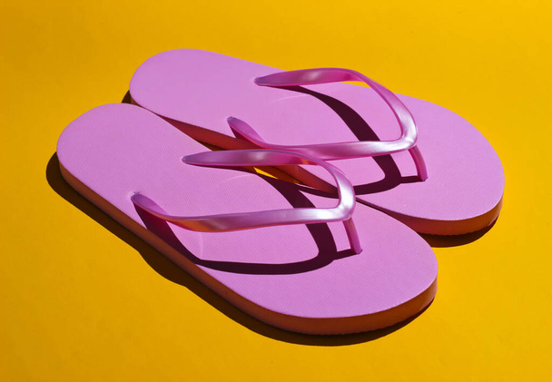 Pink flip flops on a yellow background. Fashion studio shot with shadows. - Photo, Image