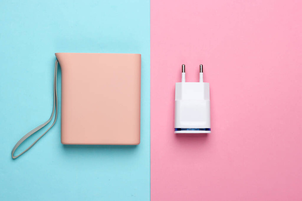 Charger with a power bank on a pink-blue pastel background. Top view - Foto, Imagem