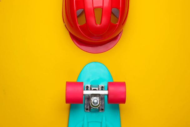 Placa de cruzador e capacete de segurança em um fundo amarelo. Equipamento de proteção para esportes. Infância. Vista superior - Foto, Imagem