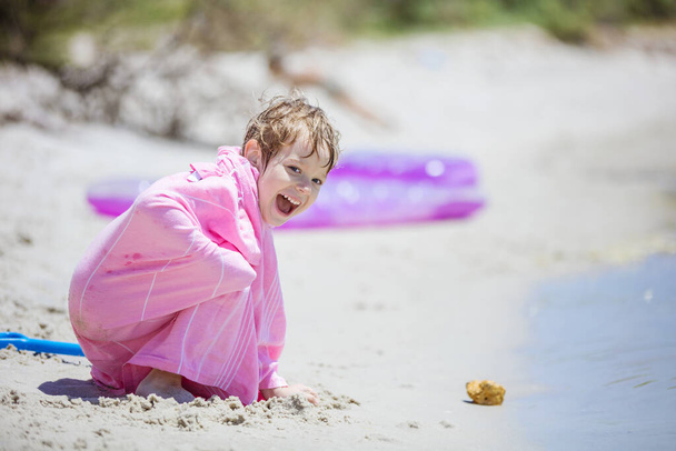 Jovem feliz na toalha de praia brincando com areia  - Foto, Imagem
