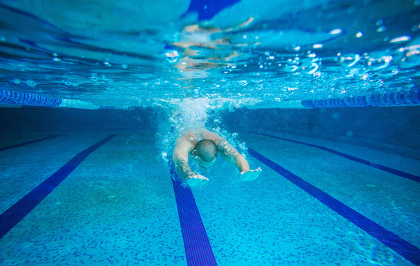 Young man swimming underwater in indoor pool - Photo, Image
