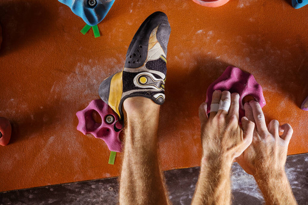 Cropped view of rock climber's hands and foot on holds in indoor climbing gym - Photo, Image