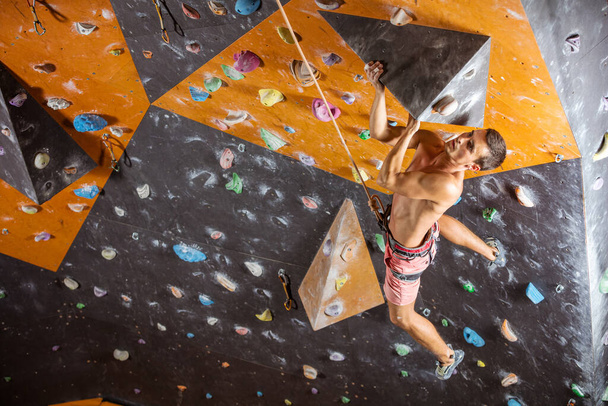 Young male rock climber on challenging route in indoor climbing gym - Zdjęcie, obraz