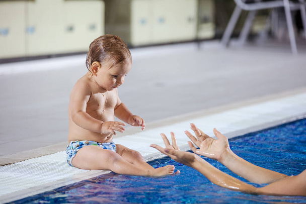 młoda kobieta złapać mały syn siedzi przy basenie w kryty basen - Zdjęcie, obraz
