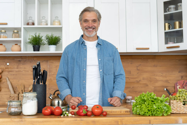 Grey-haired Mature handsome caucasian man standing in the bright kitchen - Fotoğraf, Görsel