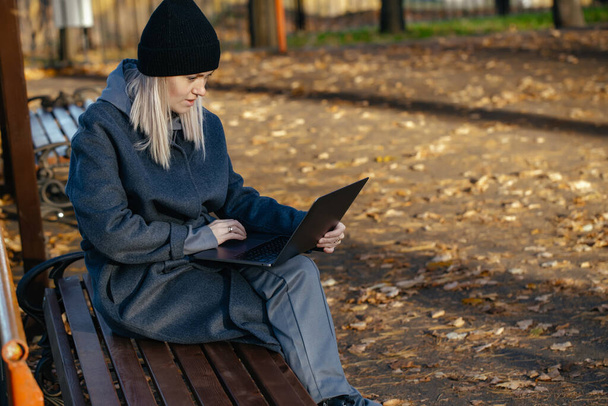 美しい白い女の子30歳公共公園に座って、ラップトップを見て - 写真・画像