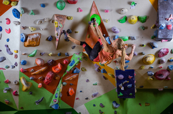 Genç bir kadın tırmanma salonunun duvarında asılı duruyor. - Fotoğraf, Görsel