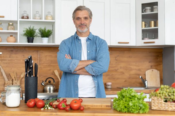 Grey-haired Mature handsome caucasian man standing in the bright kitchen - Foto, Imagem