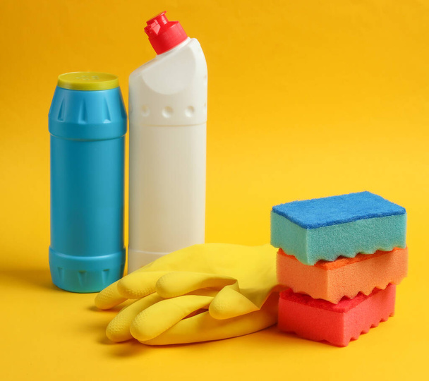 Koncepcja czyszczenia. Butelki detergentów, gąbki, rękawiczki na żółtym tle - Zdjęcie, obraz