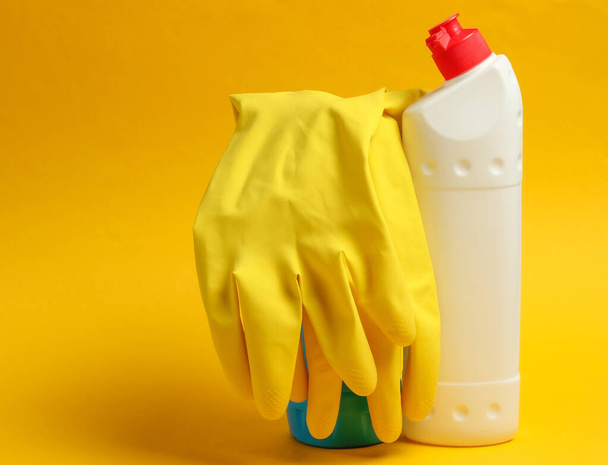 Reinigungskonzept. Waschmittelflaschen, Handschuhe auf gelbem Hintergrund - Foto, Bild