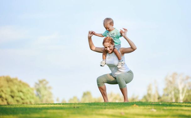 Giovane donna fitness che lavora all'aperto mentre zoccolo figlio sulle spalle - Foto, immagini