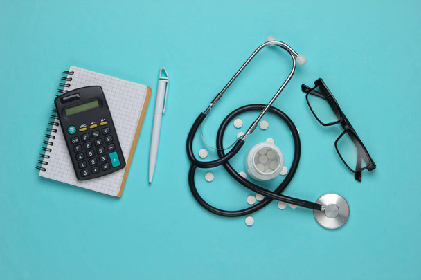 Doctoral supplies and tools, calculator on blue background. Economic calculation of the effectiveness of healthcare and medicine. Doctor workspace - Photo, Image