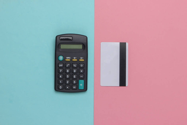 Calculadora y tarjeta bancaria sobre fondo pastel rosa azulado. Vista superior - Foto, imagen