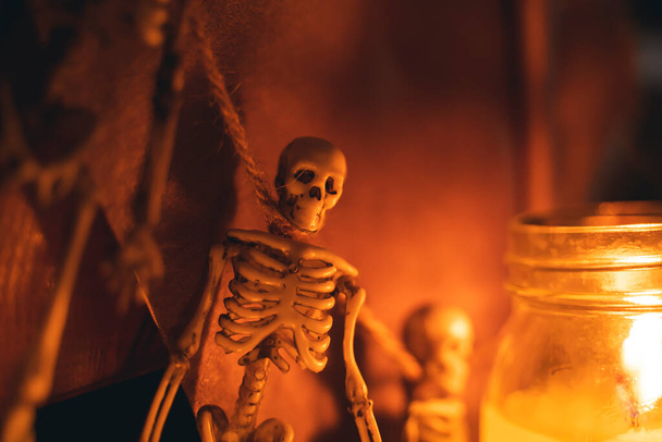 toy human skeleton hangs on a rope next to candles. Halloween-themed background - Photo, Image