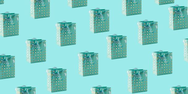 Pattern of turquoise paper bags with satin ribbon handles for gift wrapping, isolated on a blue background - Photo, image