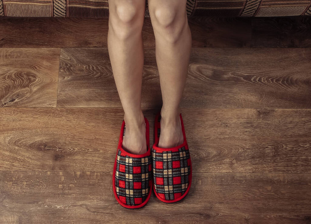 Κάτοψη των γυναικείων γυμνών ποδιών με παντόφλες σε ξύλινο πάτωμα. Εστία, αφύπνιση - Φωτογραφία, εικόνα