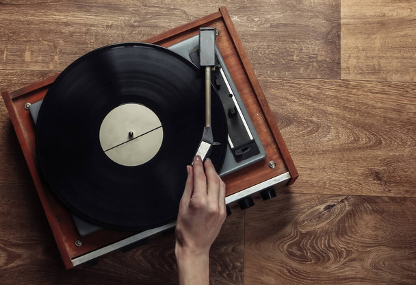 女性の手は木製の床にレトロなビニールレコードプレーヤーを設定します。音楽愛好家、 70代、郷愁、トップビュー - 写真・画像