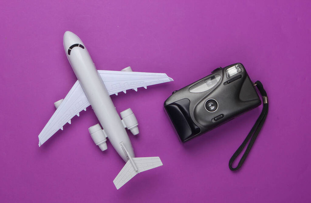 Flat lay design of travel concept with plane, camera. Purple background. Minimalism. Top view - Photo, Image
