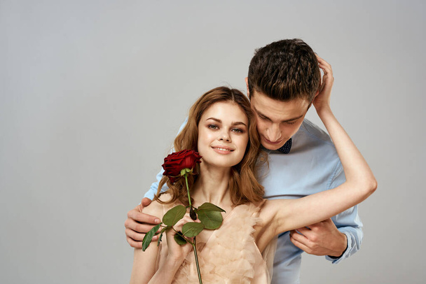 Νεαρό ζευγάρι αγκαλιάζει ρομαντική σχέση που χρονολογείται lifestyle σχέση φως φόντο κόκκινο τριαντάφυλλο - Φωτογραφία, εικόνα