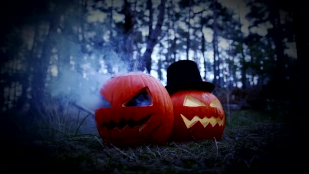 Twee griezelige gesneden pompoenen voor Halloween met rook in het bos - Video