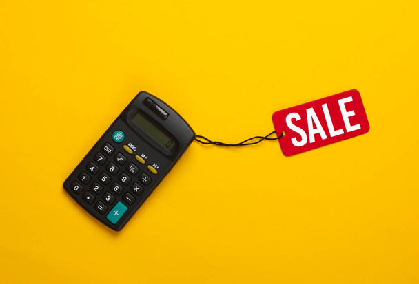 Taschenrechner mit rotem Verkaufsschild auf gelbem Hintergrund. Big Sale, Rabatte. Ansicht von oben - Foto, Bild