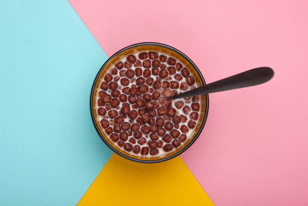 Chocolate cereal balls with milk in bowl on colored background. Concept for a healthy diet. Top view - Photo, Image