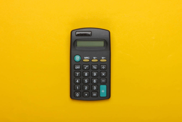 Calculadora preta em fundo amarelo. Vista superior - Foto, Imagem