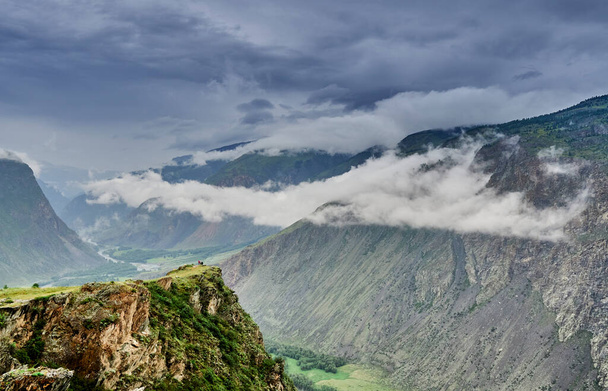 дождевые тучи над вершинами гор. отвесные скалы над речным валом; - Фото, изображение