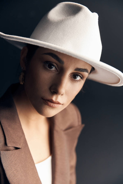 portrait photo of a beautiful stylish girl in a brown suit, white top and white hat, she mysteriously looks into the camera with her brown eyes - Fotó, kép