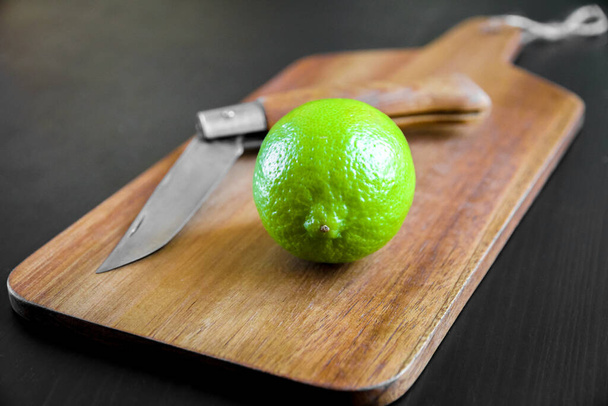 Lime and old traditional pocket knife on a wooden cutting board - Foto, Bild